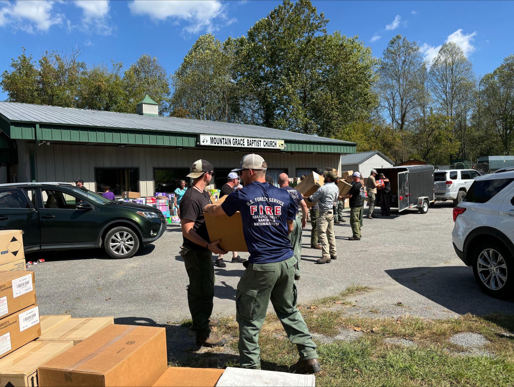 Volunteers and U.S. Forest Service crews pass boxes of relief supplies hand to hand outside a church in Marshall, North Carolina